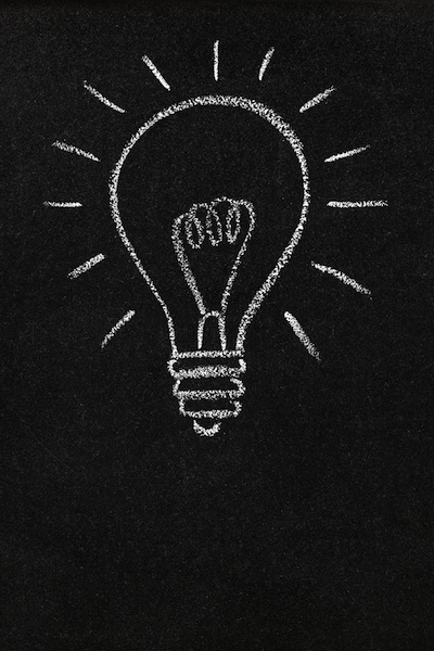 A lightbulb drawn on a chalkboard symbolizing ideas, inspiration and creativity with blank space for