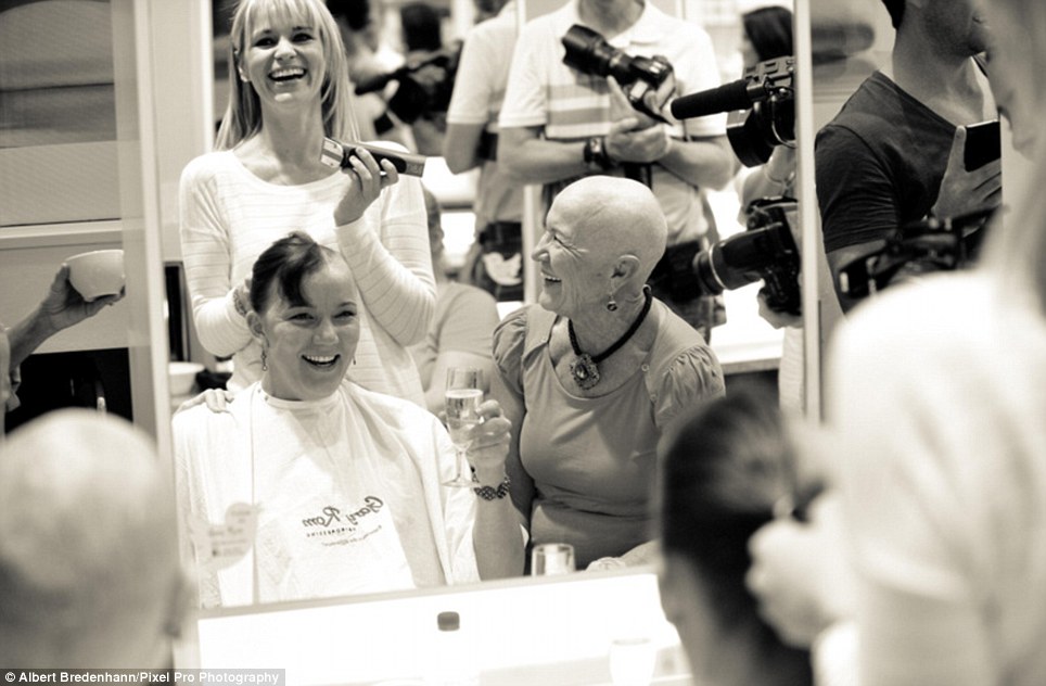 One brave woman smiles as her head is shaved. 