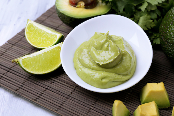 Fresh guacamole in bowl on wooden table