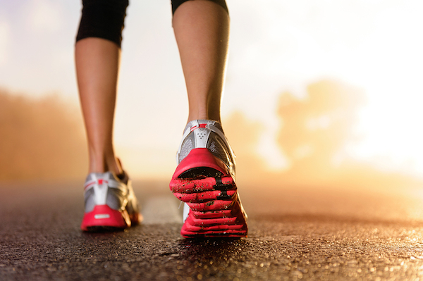 Runner feet running on road closeup on shoe. woman fitness sunrise jog workout welness concept.