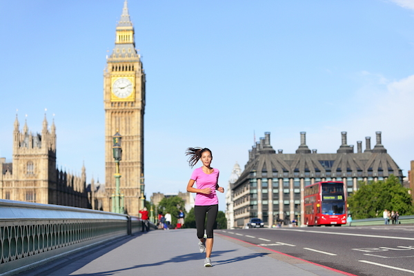 London lifestyle woman running near Big Ben. Female runner jogging training in city with red double