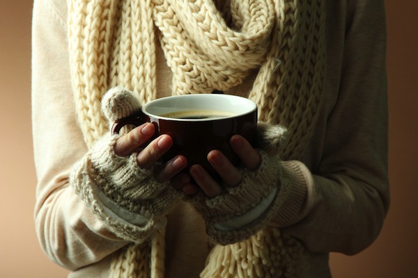 Female hands with hot drink, on color background