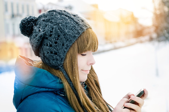 Girl looking at phone, should you wear sunscreen during winter, by Healthista.com