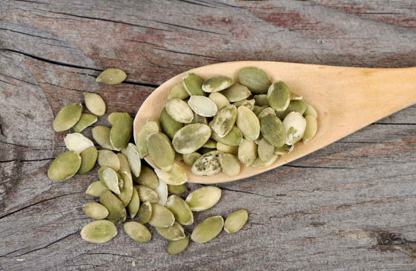 pumpkin seeds in wooden spoon, grocery list to help fight fatigue by healthista.com