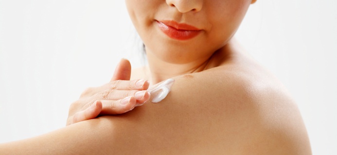 Young woman allpying moisturiser to her arm, What does hydration and moisturisation do for our skin?, by Healthista.com