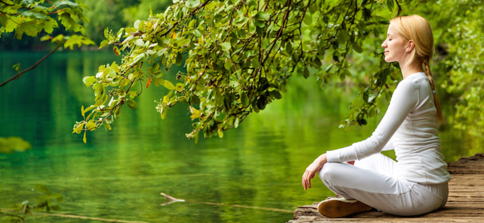 woman sitting by lake, How to meditate for beginners – a free interactive series – week 2: Being in the Here and Now by Healthista.com