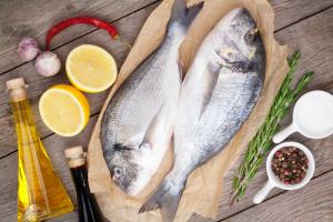 Fresh dorado fish cooking with spices and condiments on wooden table