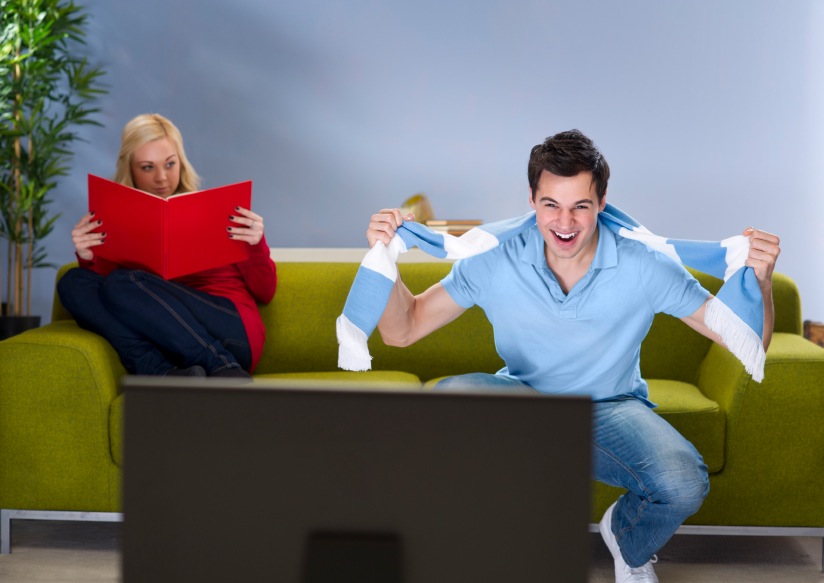 boyfriend watching football as girlfriend disapproves, relationship problems, by healthista