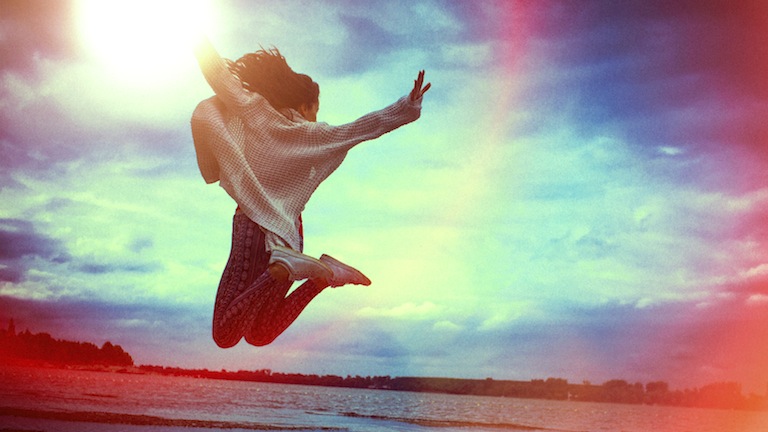 A happy young woman running and jumping on the beach, 5 secrets to success, by healthista