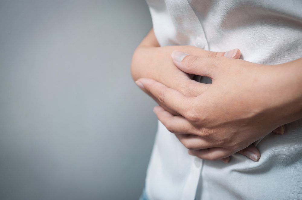 woman folding hands over stomach Why sex hurts - the gynaecologist’s guide Healthista