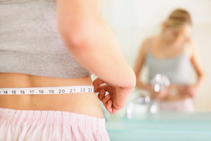 woman measuring waist 8 things naturally slim women do Healthista