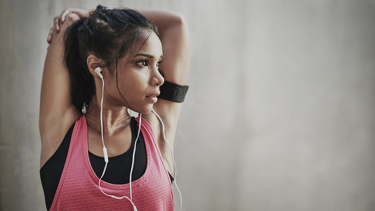 girl-stretching-arms-with-earbuds-in-20-rock-songs-thatll-pump-up-your-exercise-routine-healthista