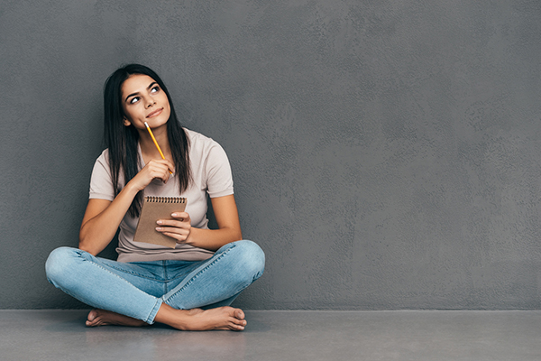 woman-sitting-and-holding-a-notebook-while-thinking-13-positive-affirmations-to-make-you-more-successful-in-life-healthista