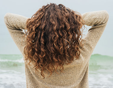 woman-standing-with-hands-in-hair-best-hair-masks-for-dry-damaged-winter-locks-healthista