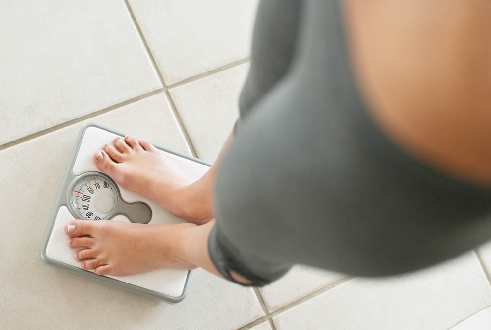 3-things-to-give-up-if-you-want-to-lose-or-maintain-your-weight-women-weighing-herself-on-scales.jpg