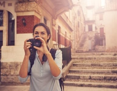 21 solo travel secrets - woman with camera - featured