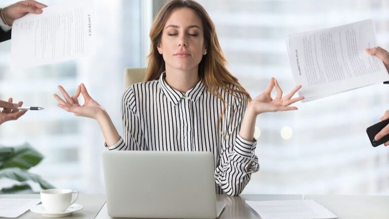 Woman meditating in the office mindfulness at work main post