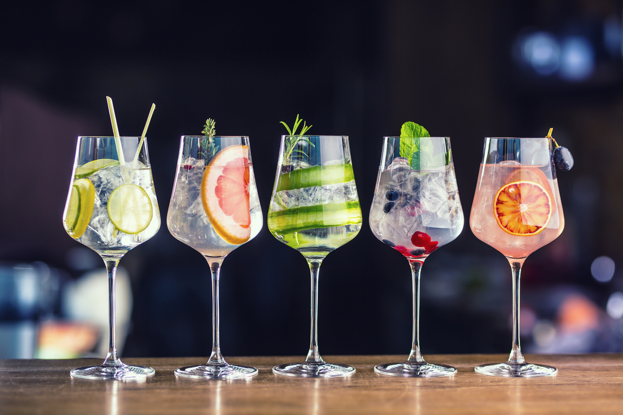 Five colorful gin tonic cocktails in wine glasses on bar counter in pup or restaurant.healthista.Healthbenifitsofdryjanuary