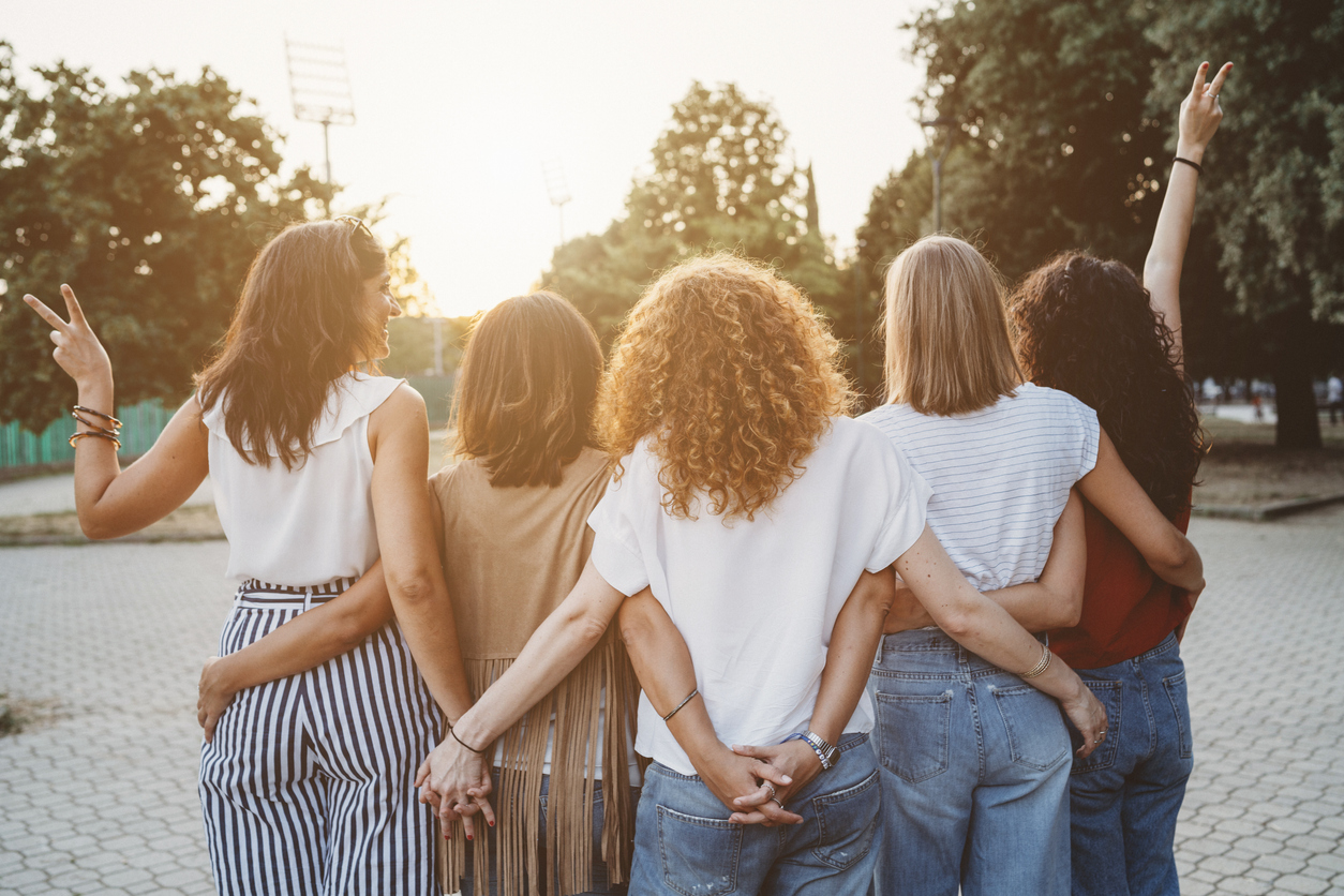 Group of women friends holding hands together against sunset.Healthista.Feature.healthBeniftsofdryjanuary