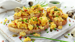 Homemade Quail Scrambled eggs on crispy toast, bread with green onion, chives on white board