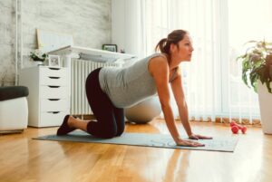 7 osteopath recommended morning stretches pregnant woman in cat cow pose