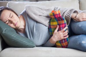 Endometriosis symptoms Here's what you need to know women laying with hot water bottle on stomach