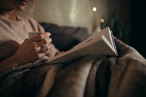 woman reading book and drinking tea before bed health rituals