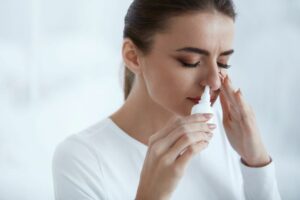 woman using nasal spray hay fever season