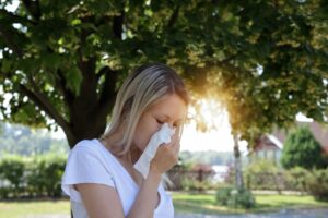 hay fever jubilee bank holiday weekend woman with tissue in park