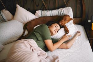 woman asleep with her dog insomnia